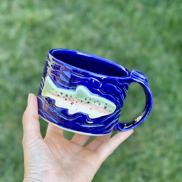 Rainbow Trout Mug in Cobalt — A deep cobalt mug with a sculpted, hand-painted rainbow trout
